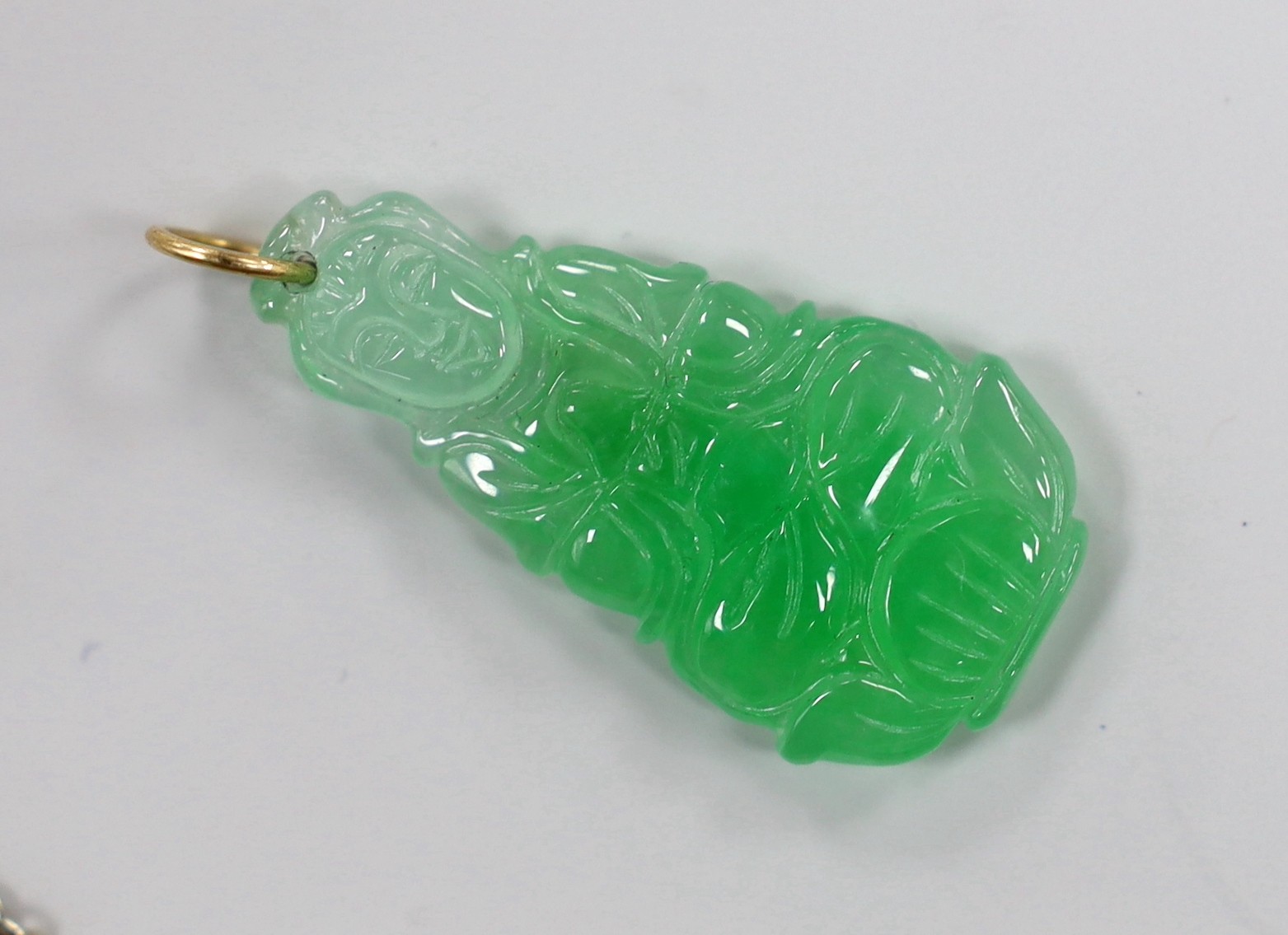 Two carved jade pendants, largest 47mm on a white metal chain.